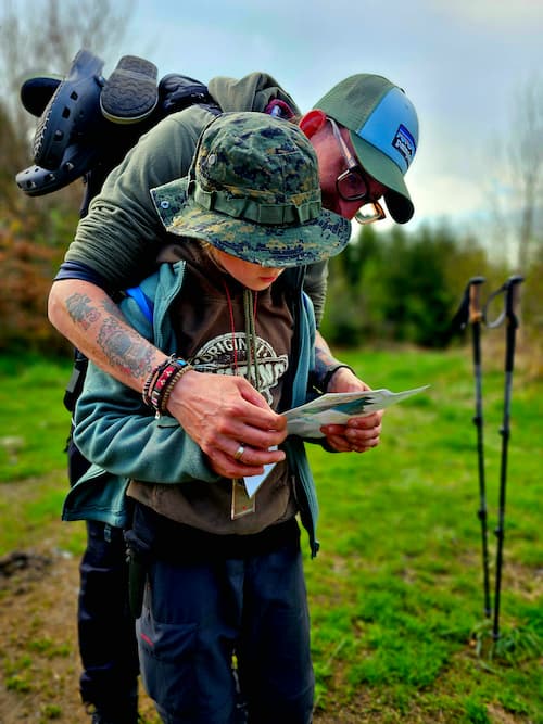 Een volwassene en kind lezen samen een kaart tijdens een navigatie oefening.